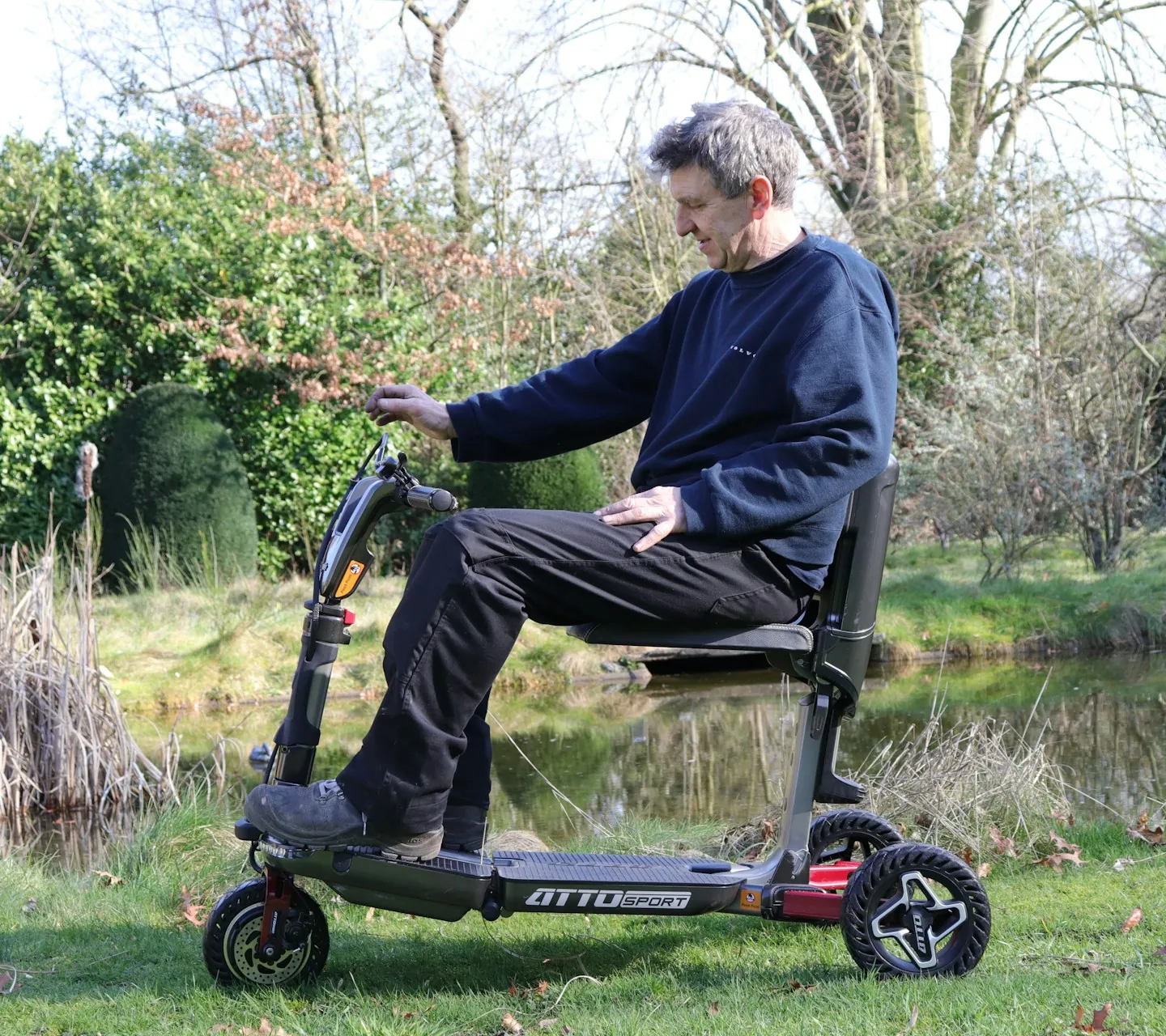 Man riding a hired mobility scooter along a sunny path