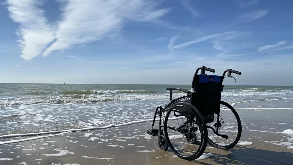 Rollstuhl im Sand direkt am Wasser